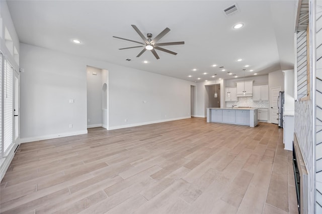 9306 Eckert Rd, Iowa Colony, TX 77583 - unfurnished living room with ceiling fan, baseboards, light wood-style floors, and visible vents