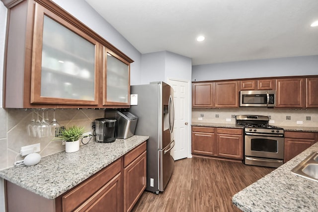 kitchen featuring light stone counters, tasteful backsplash, appliances with stainless steel finishes, and dark wood-type flooring