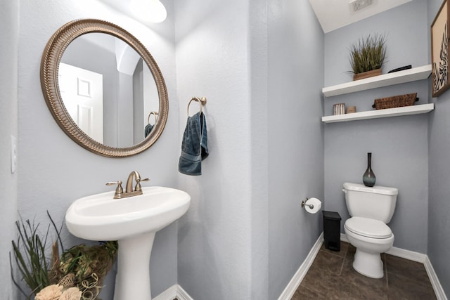 half bath featuring a sink, toilet, visible vents, baseboards, and tile patterned flooring
