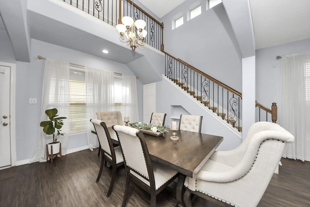 dining area featuring a chandelier, stairs, baseboards, a towering ceiling, and wood finished floors