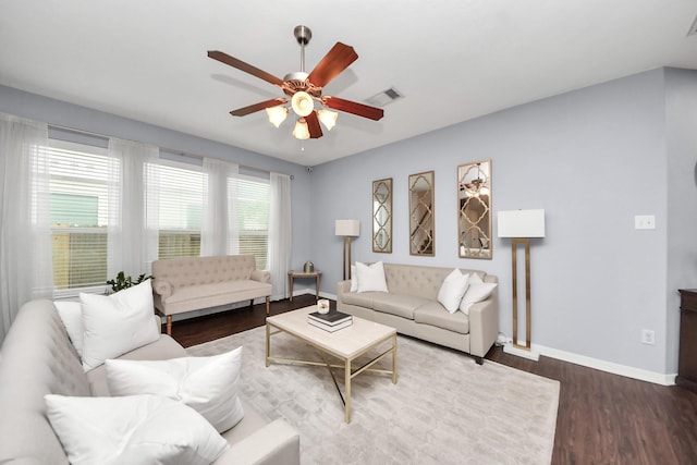 living room with baseboards, visible vents, wood finished floors, and a ceiling fan