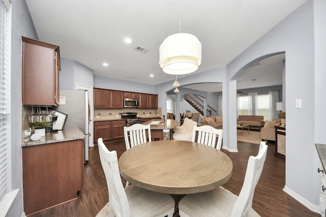 dining room with recessed lighting, dark wood-type flooring, stairs, visible vents, and arched walkways