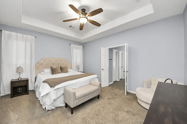 carpeted bedroom with a raised ceiling, ceiling fan, visible vents, and baseboards