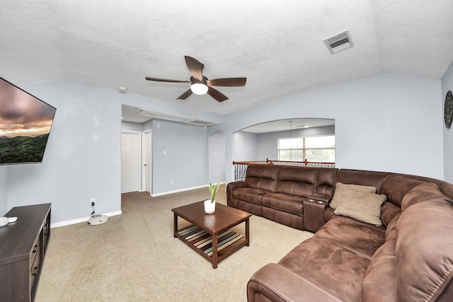 carpeted living room with ceiling fan, visible vents, vaulted ceiling, baseboards, and a textured ceiling