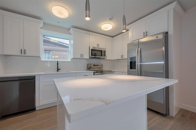kitchen with a sink, light wood-style flooring, backsplash, and stainless steel appliances