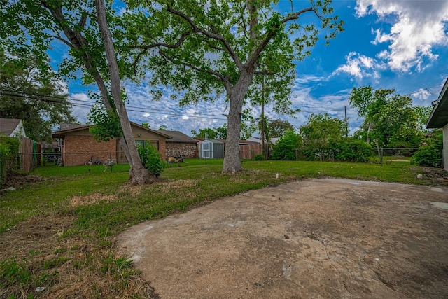view of yard with an outdoor structure, a fenced backyard, and a storage shed