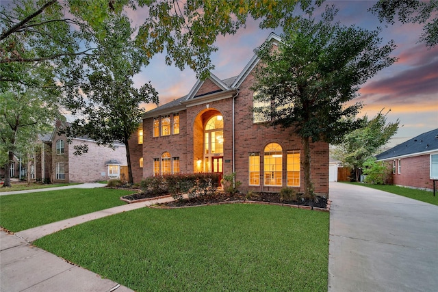 traditional-style home with a lawn, concrete driveway, and brick siding