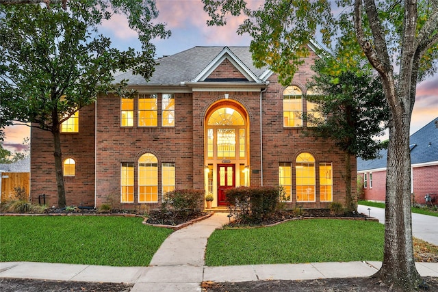 view of front of house featuring a yard and brick siding
