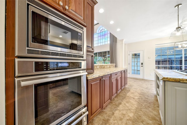 kitchen with light tile patterned floors, light stone countertops, decorative light fixtures, and stainless steel appliances