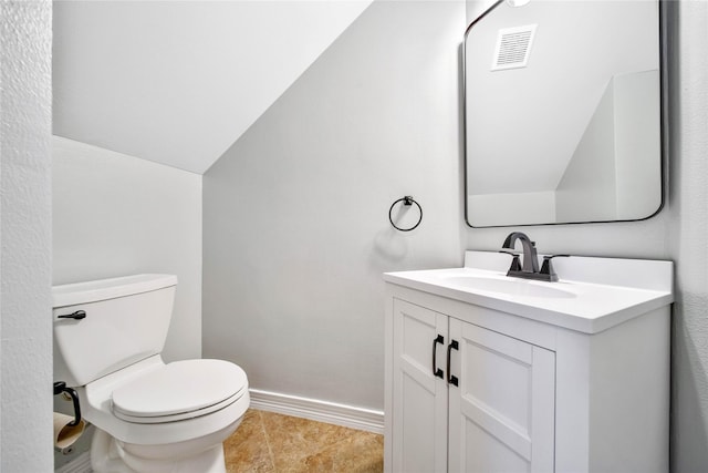half bathroom with vanity, toilet, visible vents, baseboards, and lofted ceiling