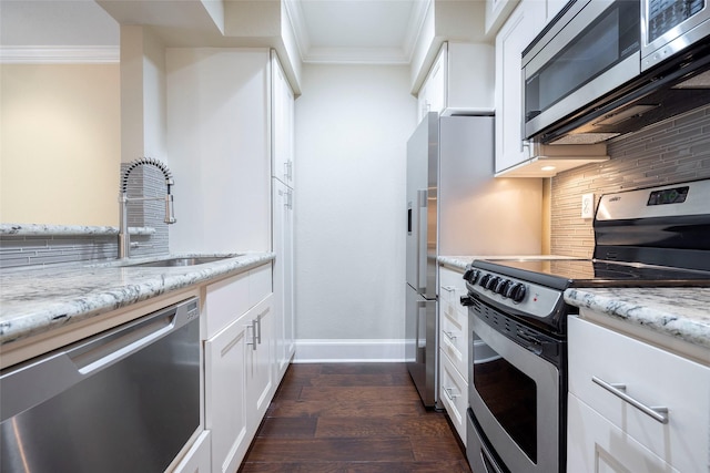 kitchen featuring dark wood-style floors, a sink, stainless steel appliances, backsplash, and ornamental molding