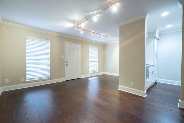unfurnished room featuring dark wood-type flooring, baseboards, rail lighting, and crown molding