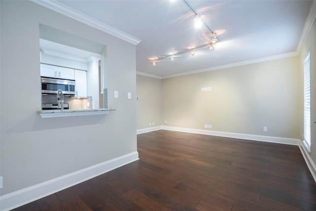 interior space with ornamental molding, track lighting, baseboards, and dark wood-type flooring
