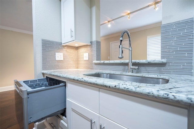 kitchen with white cabinetry, ornamental molding, and a sink