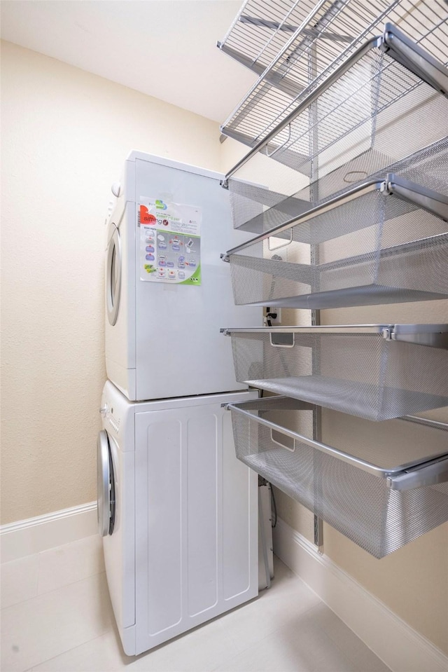 laundry room with baseboards, stacked washer / dryer, and laundry area