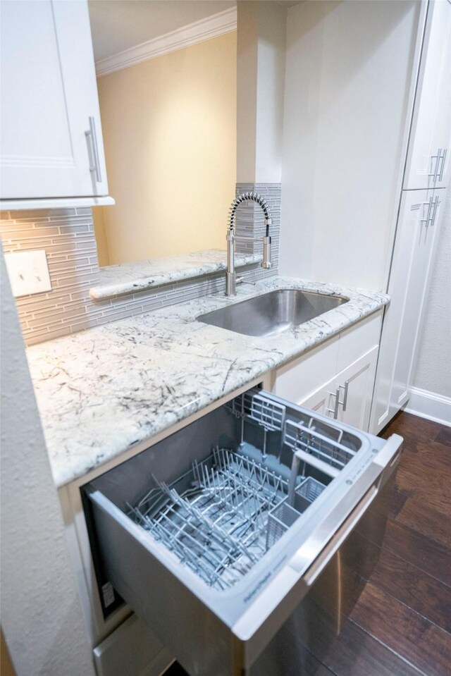 kitchen featuring crown molding, light stone countertops, a sink, and backsplash