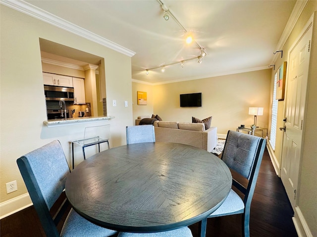 dining room with crown molding, dark wood-style floors, track lighting, and baseboards