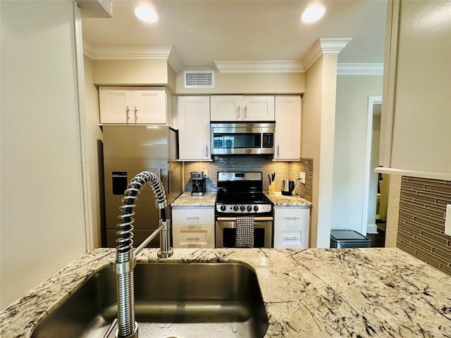 kitchen featuring tasteful backsplash, appliances with stainless steel finishes, a sink, visible vents, and crown molding