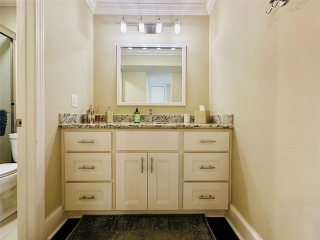 bathroom with ornamental molding, toilet, vanity, and baseboards