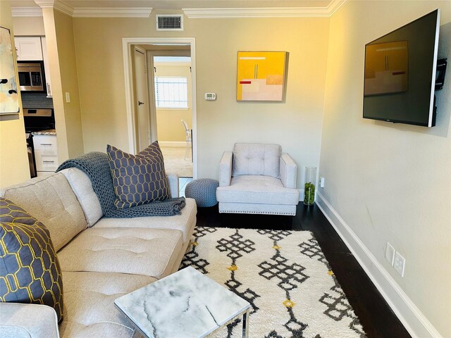 living area with wood finished floors, visible vents, and ornamental molding