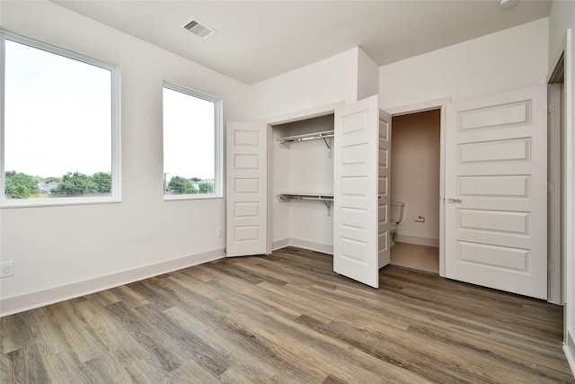 unfurnished bedroom featuring baseboards, visible vents, wood finished floors, and a closet