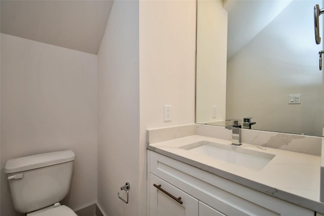 bathroom featuring toilet, vaulted ceiling, and vanity