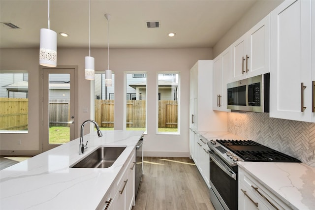 kitchen featuring visible vents, stainless steel appliances, light wood finished floors, and a sink