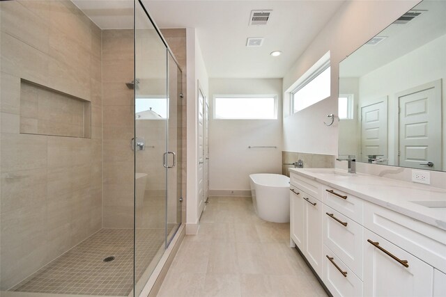 full bathroom with a sink, a freestanding tub, a stall shower, double vanity, and visible vents