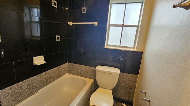 full bathroom featuring a textured wall, toilet, and plenty of natural light