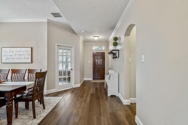 doorway with arched walkways, baseboards, crown molding, and wood finished floors