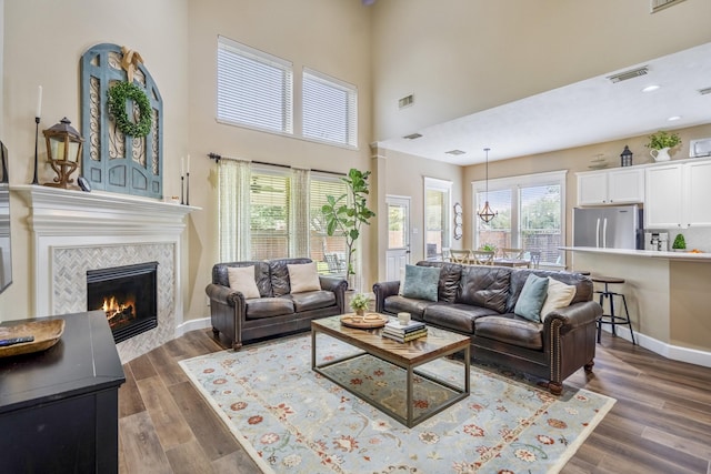 living area featuring a high ceiling, a fireplace, dark wood-style flooring, baseboards, and recessed lighting