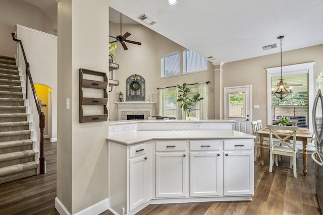kitchen with ceiling fan, dark wood-style floors, a peninsula, healthy amount of natural light, and a high ceiling