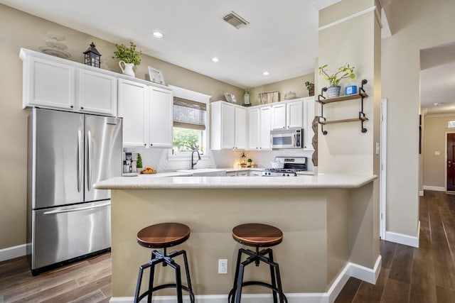 kitchen with stainless steel appliances, a sink, dark wood-style floors, white cabinets, and recessed lighting