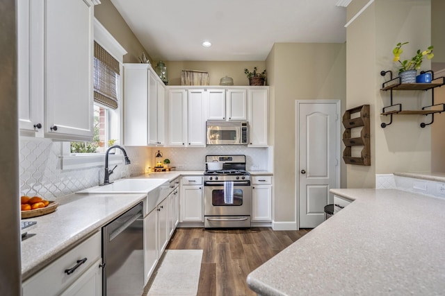 kitchen with stainless steel appliances, dark wood-style flooring, white cabinets, a sink, and recessed lighting
