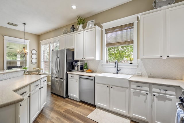 kitchen featuring appliances with stainless steel finishes, white cabinets, plenty of natural light, light wood-type flooring, and recessed lighting