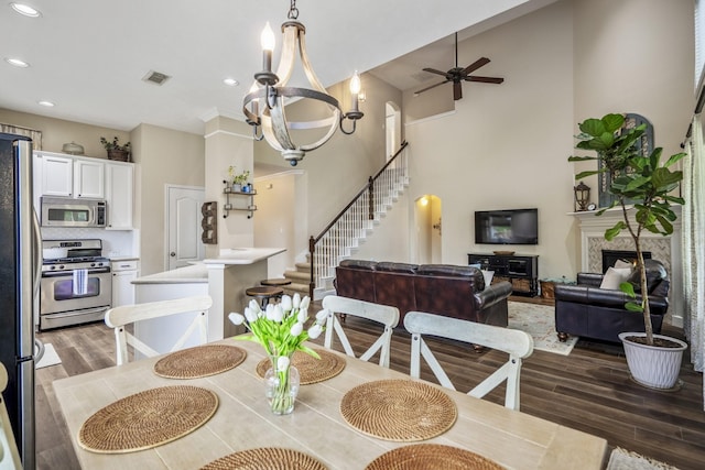 dining area featuring wood finished floors, stairs, ceiling fan, a premium fireplace, and recessed lighting