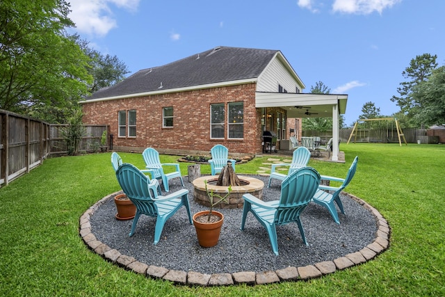 back of property featuring a fire pit, brick siding, ceiling fan, a patio area, and a playground