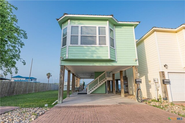106 Clement Cv, Port Lavaca, TX 77979 - coastal home with a front lawn, a carport, stairs, concrete driveway, and fence