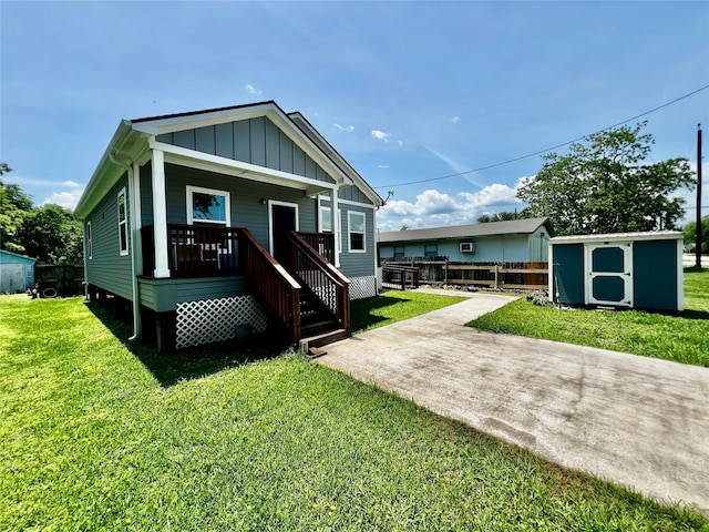 view of front facade with board and batten siding, a storage unit, an outbuilding, a front yard, and a porch