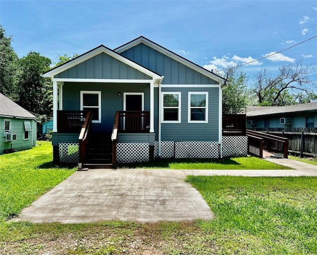 bungalow-style house featuring board and batten siding, a porch, a front yard, and cooling unit