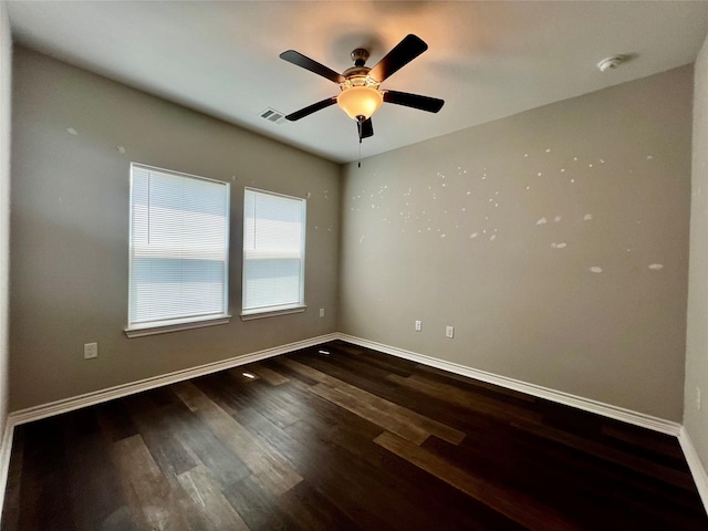 unfurnished room with a ceiling fan, visible vents, wood finished floors, and baseboards