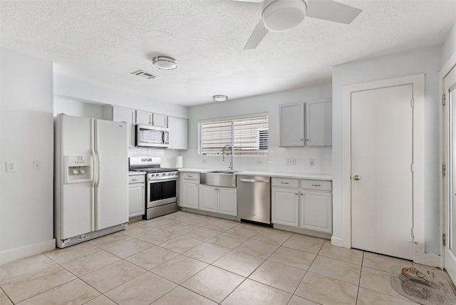 kitchen featuring ceiling fan, appliances with stainless steel finishes, a sink, light countertops, and visible vents