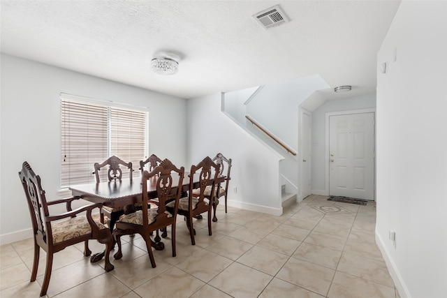 dining area with a textured ceiling, stairs, baseboards, light tile patterned floors, and visible vents