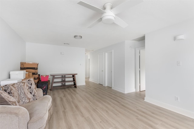 sitting room featuring a ceiling fan, baseboards, and light wood-style flooring