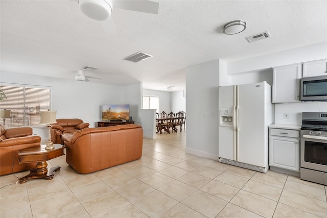 living area with a textured ceiling, ceiling fan, and visible vents
