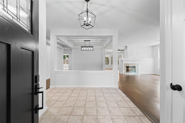 entrance foyer with a tiled fireplace, baseboards, an inviting chandelier, and light tile patterned flooring
