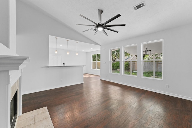 unfurnished living room with visible vents, ceiling fan, hardwood / wood-style flooring, and a fireplace with flush hearth