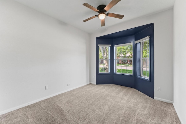 carpeted empty room featuring a ceiling fan and baseboards