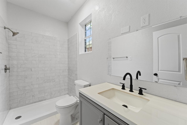 bathroom with tiled shower, toilet, and vanity