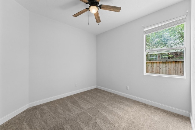 carpeted spare room featuring a ceiling fan and baseboards